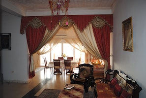 A room with a dining area, a sofa, and a chandelier.