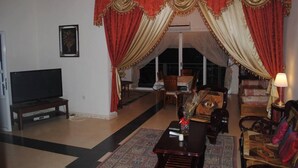 A living room with a television, a dining table with chairs, and a sofa.