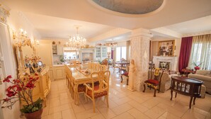 Een ruime woonkamer met een eethoek, een open haard en een keuken op de achtergrond.