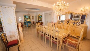 Een formele eetzaal met een grote tafel, versierde stoelen en een kroonluchter.
