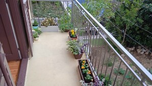 Uma varanda estreita com plantas em vasos e guarda-corrimão de metal.