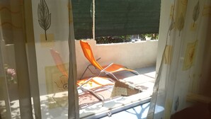 Janela com vista para área externa, incluindo uma cadeira e uma mesa.