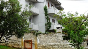 A two-story house with a stone wall, a wooden gate, and a flower pot. - Modern apartment with amazing view (Trogir)