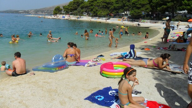 A beach with people sunbathing and swimming. - Modern apartment with amazing view (Trogir)