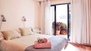 Ein Hotelzimmer mit einem Bett, zwei Nachttischlampen, einem Fenster mit Vorhängen und Blick nach draußen.