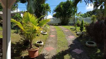 A garden pathway with potted plants and a white fence in the background.