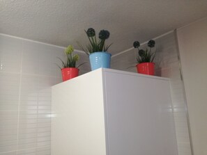 Um armário branco com três plantas em vasos sobre ele.