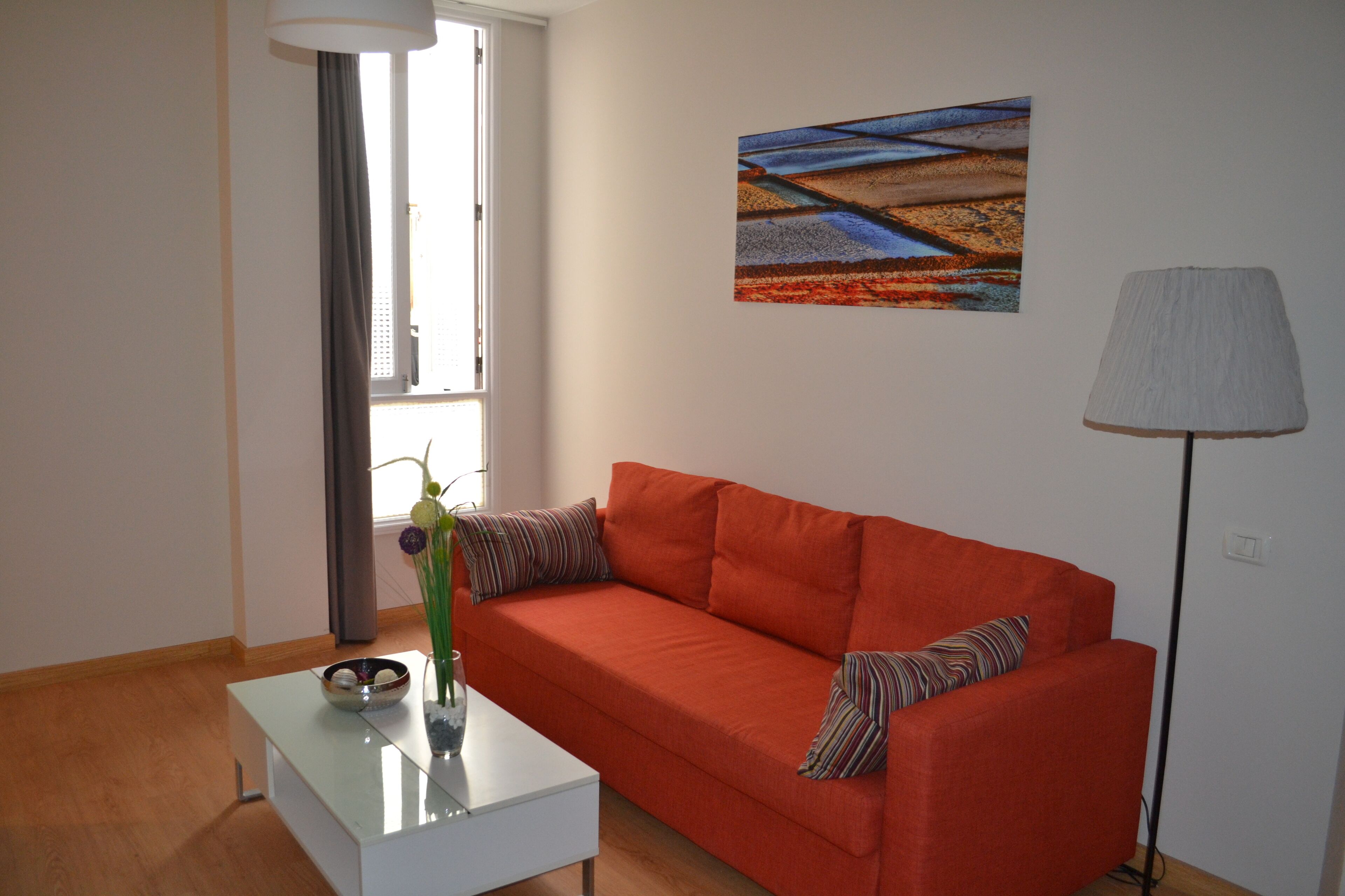 Una sala de estar moderna con un sofá rojo, una mesa de centro blanca y un cuadro en la pared.