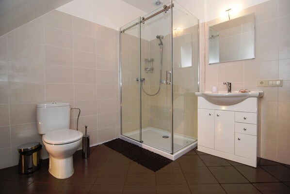 A modern bathroom with a glass-enclosed shower, a toilet, and a sink with cabinets.