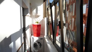 Un área de lavandería con lavadora, una cesta roja y un trapeador.