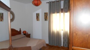 Un dormitorio con cama, cómoda de madera, mesita de noche, una pelota de baloncesto y una pared con tres cuadros.