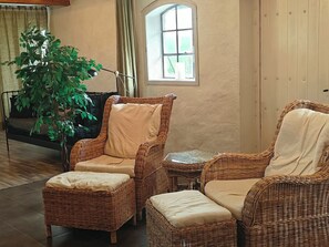 A room with wicker furniture, a potted plant, and a window. - Unique living in converted horse stable (Ystad V)