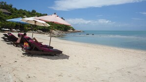 A beach with sun loungers and umbrellas, a clear sky, and calm sea. - Junior Pool Villa in Beach resort (Ko Samui)