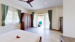 A hotel room with a bed, a wardrobe, a ceiling fan, and a view of the outdoor area. - Junior Pool Villa in Beach resort (Ko Samui)