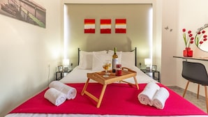 Ein Hotelzimmer mit einem Bett, einem Tablett mit einer Flasche und Gläsern, Handtüchern und einem Bild an der Wand.