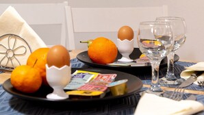 Ein Esstisch mit einer Schale Orangen, einem Ei und einem Weinglas.