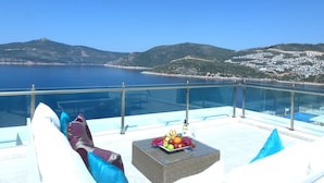 A terrace with a glass balustrade overlooking a coastal landscape.