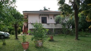 A two-story building with a garden in front. There are potted plants and a car parked nearby. - Looking for a quiet place? VILLA CASCIANI (Diecimo)