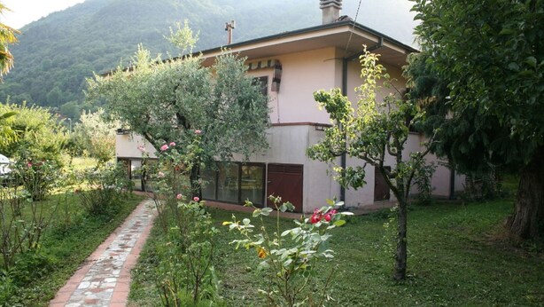 A building with a stone pathway leading to a door, surrounded by lush greenery and trees. - Looking for a quiet place? VILLA CASCIANI (Diecimo)