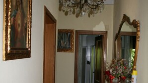 A hallway with a wooden floor, a chandelier, a mirror, and a framed painting on the wall. - Looking for a quiet place? VILLA CASCIANI (Diecimo)