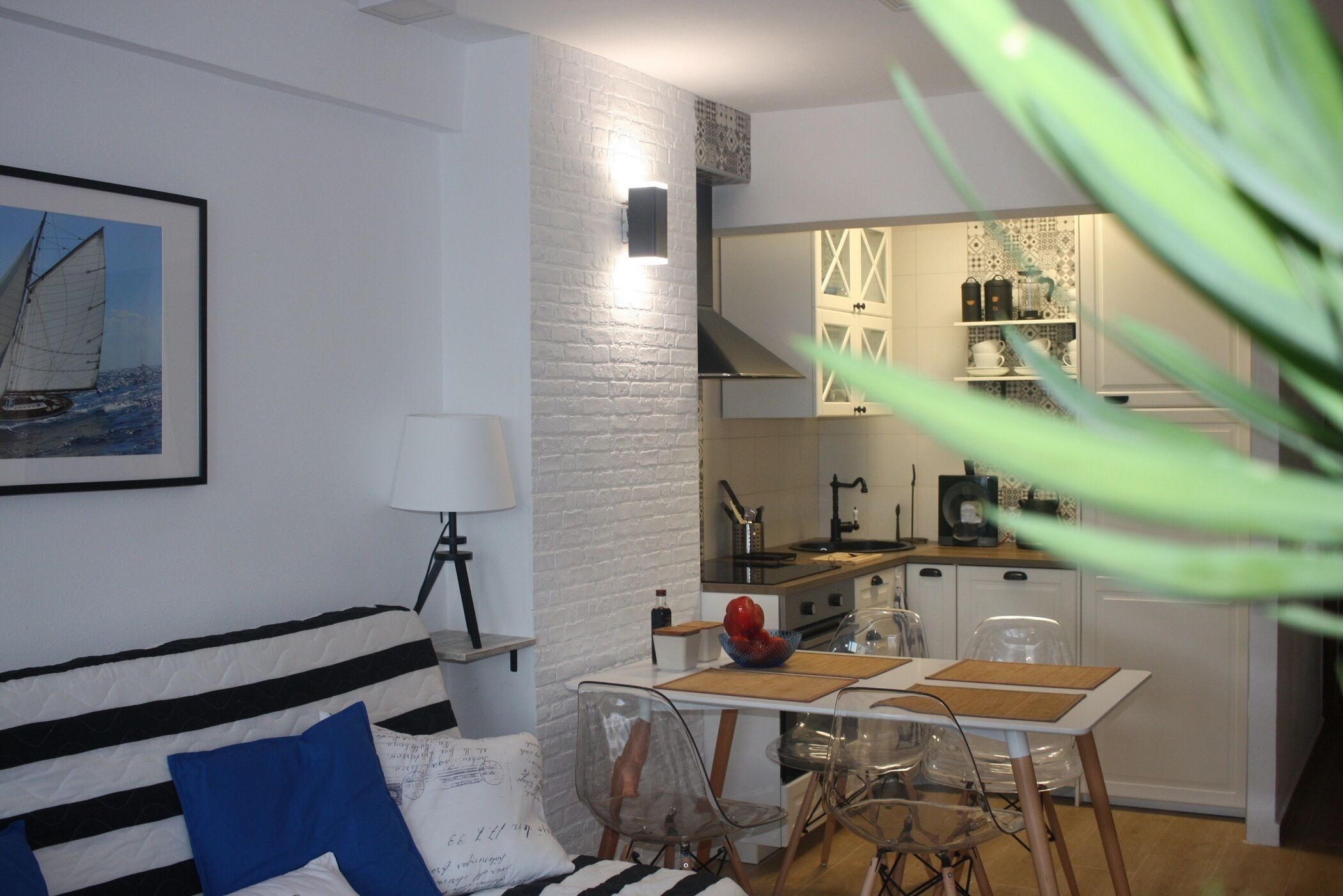 Un salon moderne comprenant un canapé, une table à manger et un coin cuisine avec une cuisinière et des placards.
