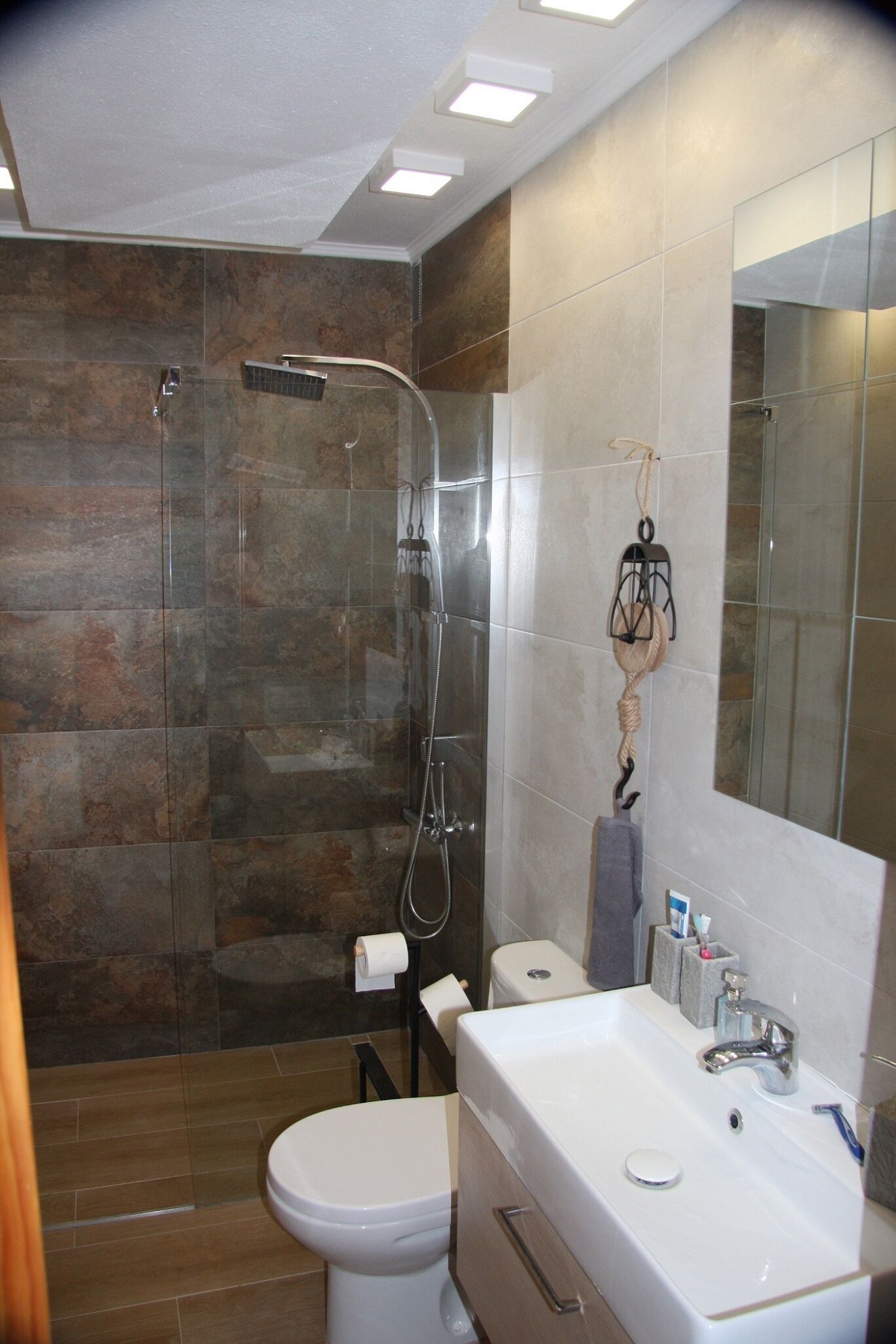Een moderne badkamer met een douchecabine van glas, een wit wastafelmeubel en een toilet.