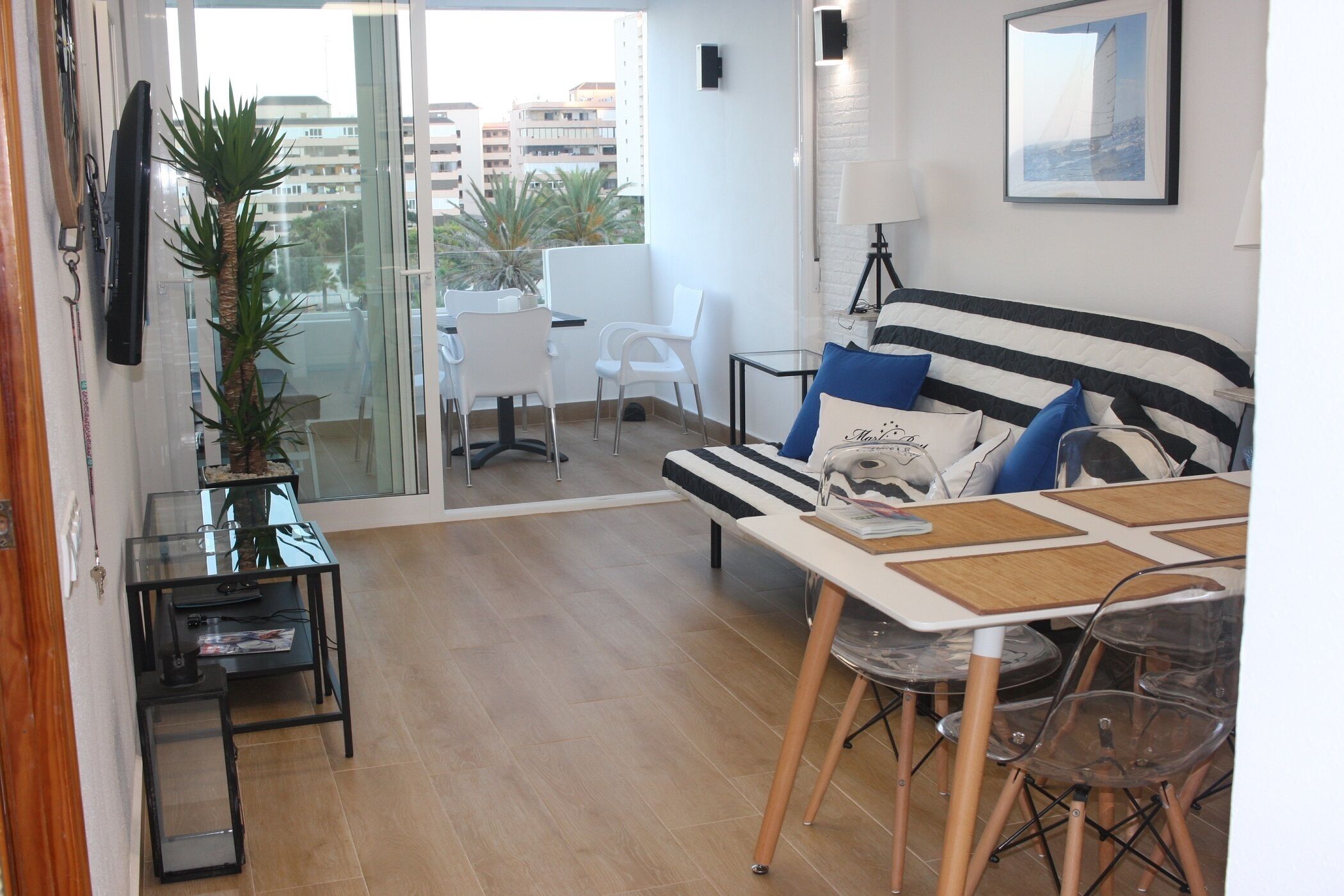 Un salon moderne avec un canapé, une table à manger, des chaises, une petite télévision et une plante en pot.