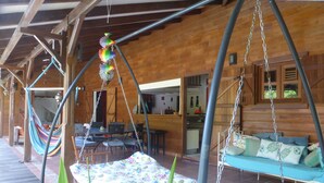 Una cabaña de madera con una hamaca, un columpio y una zona de comedor.