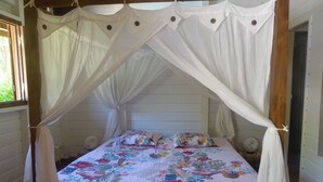Una cama con dosel y cortinas, ropa de cama floral y cabecera de madera.