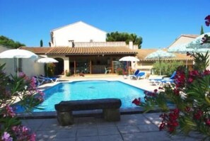 A swimming pool with lounge chairs and umbrellas, surrounded by flowers and a bench. - Gite 2/3 persons in Provence, 10 km from Avignon. (Saint-Saturnin-Lès-Avignon)