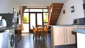 Een compacte keuken met een wasmachine, een magnetron en een eethoek met een tafel en stoelen.