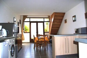 A compact kitchen with a washing machine, a microwave, and a dining area with a table and chairs. - Gite 2/3 persons in Provence, 10 km from Avignon. (Saint-Saturnin-Lès-Avignon)
