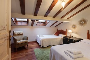 A bedroom with two beds, a chair, a skylight, and a wooden ceiling. - Rural house in the heart of Asturias, Comarca de la Sidra, a step away from everything (Cabranes)