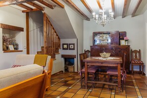 Una stanza accogliente con un divano in legno, un tavolo da pranzo con sedie, un lampadario e una scala.