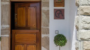 Eine Holztür mit Klingelschild, kleinem Schild und einer Topfpflanze.