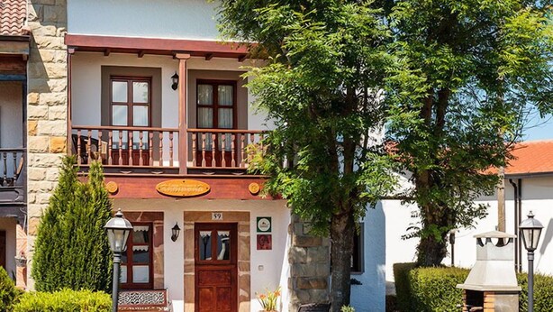 Ein traditionelles Gebäude mit Balkon, Steinfassade und einer hölzernen Einfriedung davor.