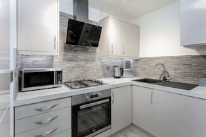 A modern kitchen with stainless steel appliances, a flat-screen TV, and a built-in oven.