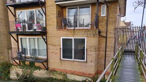 A multi-story brick building with balconies, a wooden deck, and a canal. - Waterfront apartment in the Heart of St Neots (St Neots, Cambs)
