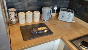 A kitchen with a wooden countertop, a kettle, a toaster, and containers labeled coffee, sugar, and tea. - Waterfront apartment in the Heart of St Neots (St Neots, Cambs)