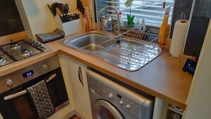 A compact kitchen with a stove, oven, sink, and a built-in washing machine. - Waterfront apartment in the Heart of St Neots (St Neots, Cambs)