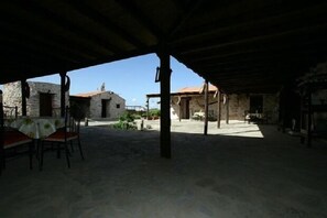 An outdoor patio area with stone buildings in the background, a table with chairs, and a covered seating area. - La Gayra Agritourism, The Graft (Tuineje)