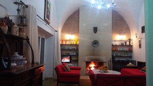 Ein gemütliches Wohnzimmer mit Kamin, roten Möbeln und Regalen mit dekorativen Gegenständen.
