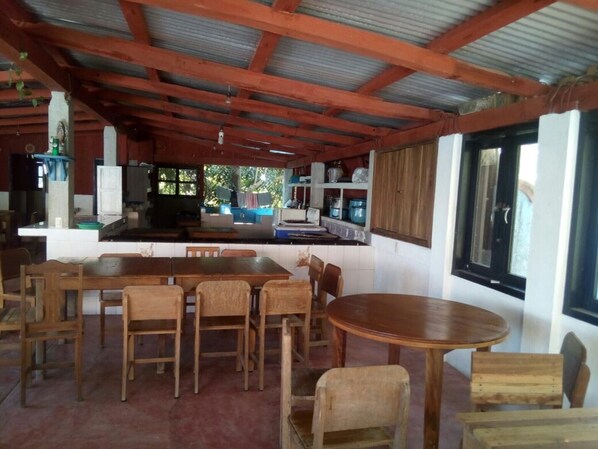 A rustic kitchen with wooden furniture, a dining area with a round table, and a large window.