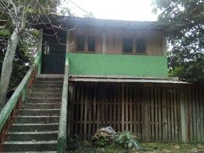 A two-story building with a green upper level and a lower level with a corrugated metal roof.