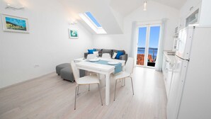 A bright, modern room with a dining table, grey sofa, and a view of the sea through large windows. - Penthouse apartment Sea (Bol)