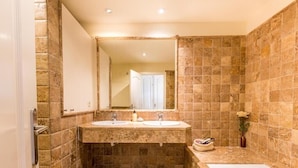 Un baño con dos lavamanos, una bañera y un espejo grande.