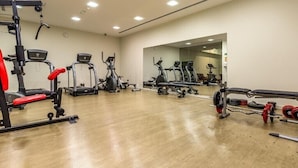 Un gimnasio con equipos de ejercicio variados, incluyendo cintas de correr, máquinas de pesas y pesas libres.
