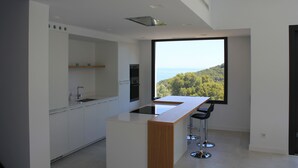 Eine moderne Küche mit großem Fenster, weißen Schränken und einer Bar.