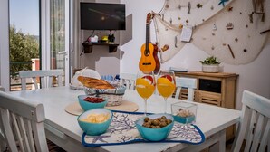 A dining table with food and drinks, a guitar, and a wall decorated with nautical items.