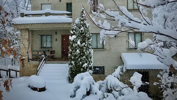 Ein zweistöckiges Gebäude mit schneebedecktem Dach und einer Treppe, die zum Eingang führt.